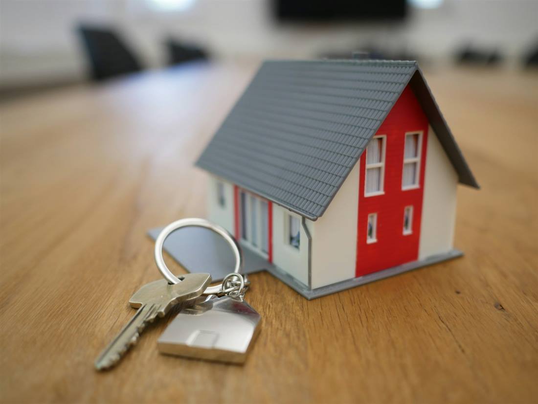 Llaves y maqueta de casa sobre un escritorio de agencia inmobiliaria